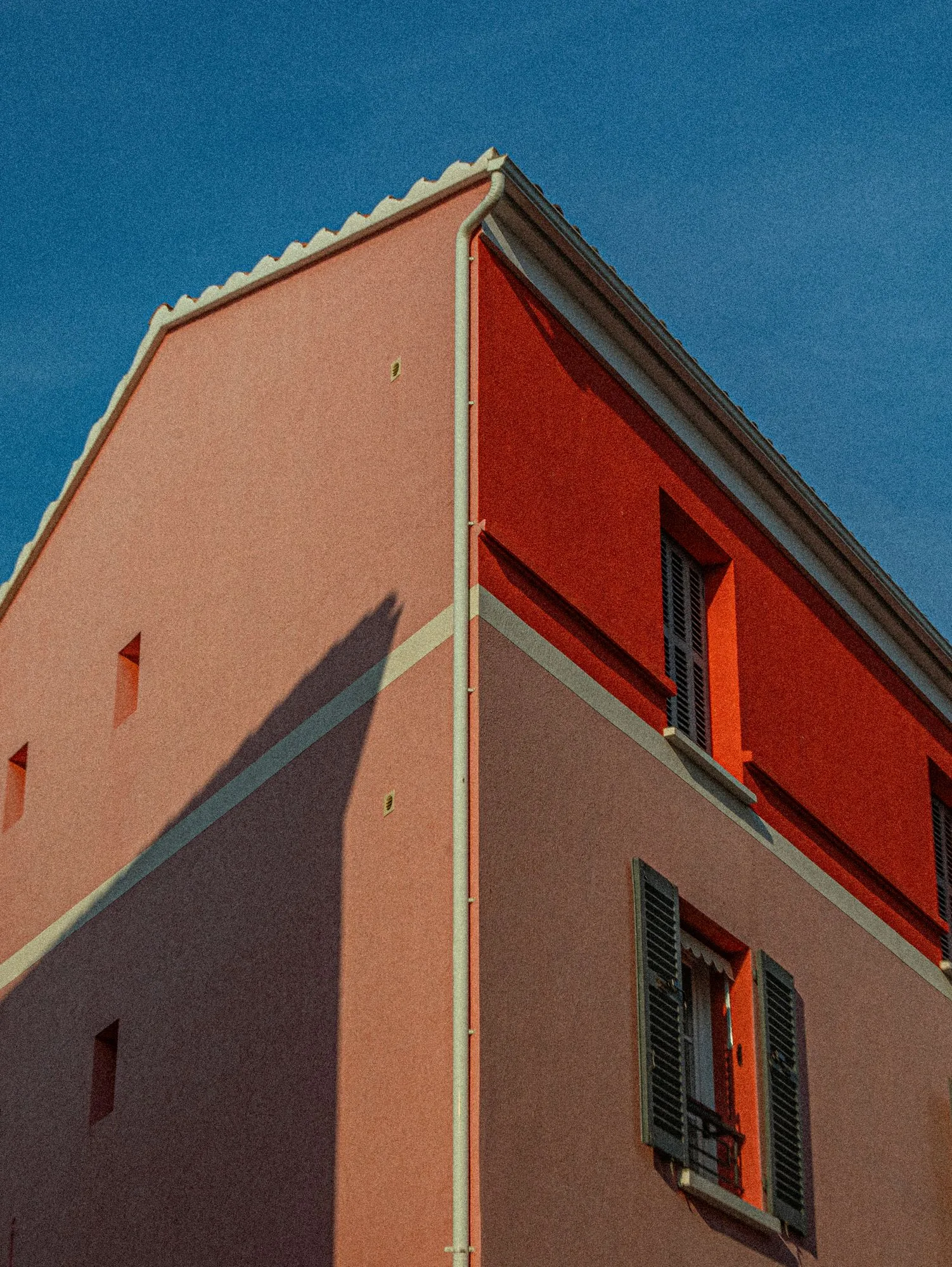 Angle d'une maison rose et rouge sous le ciel bleu