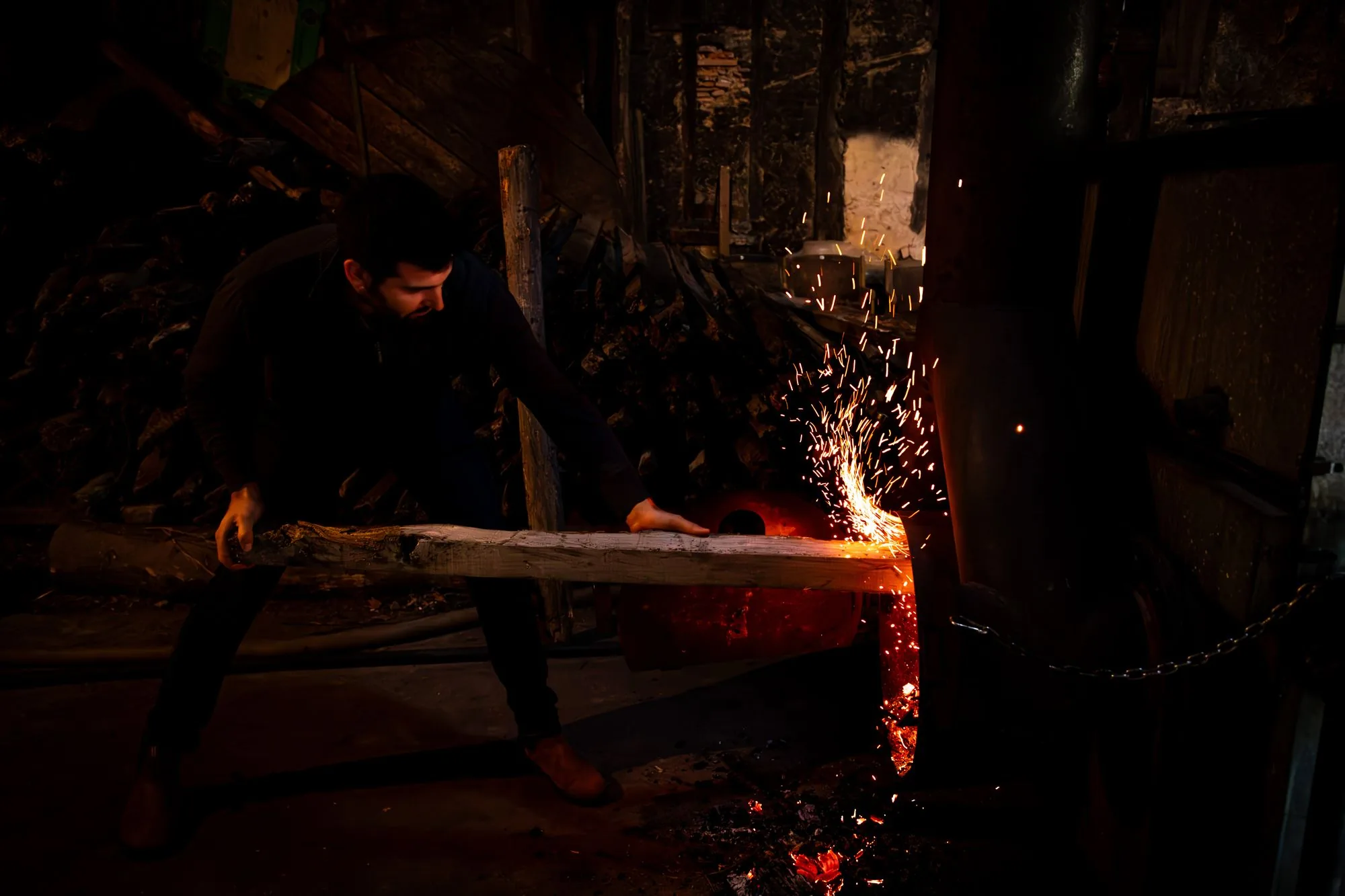 Le distillateur alimente le feu de l'alambic, gerbe d'étincelles