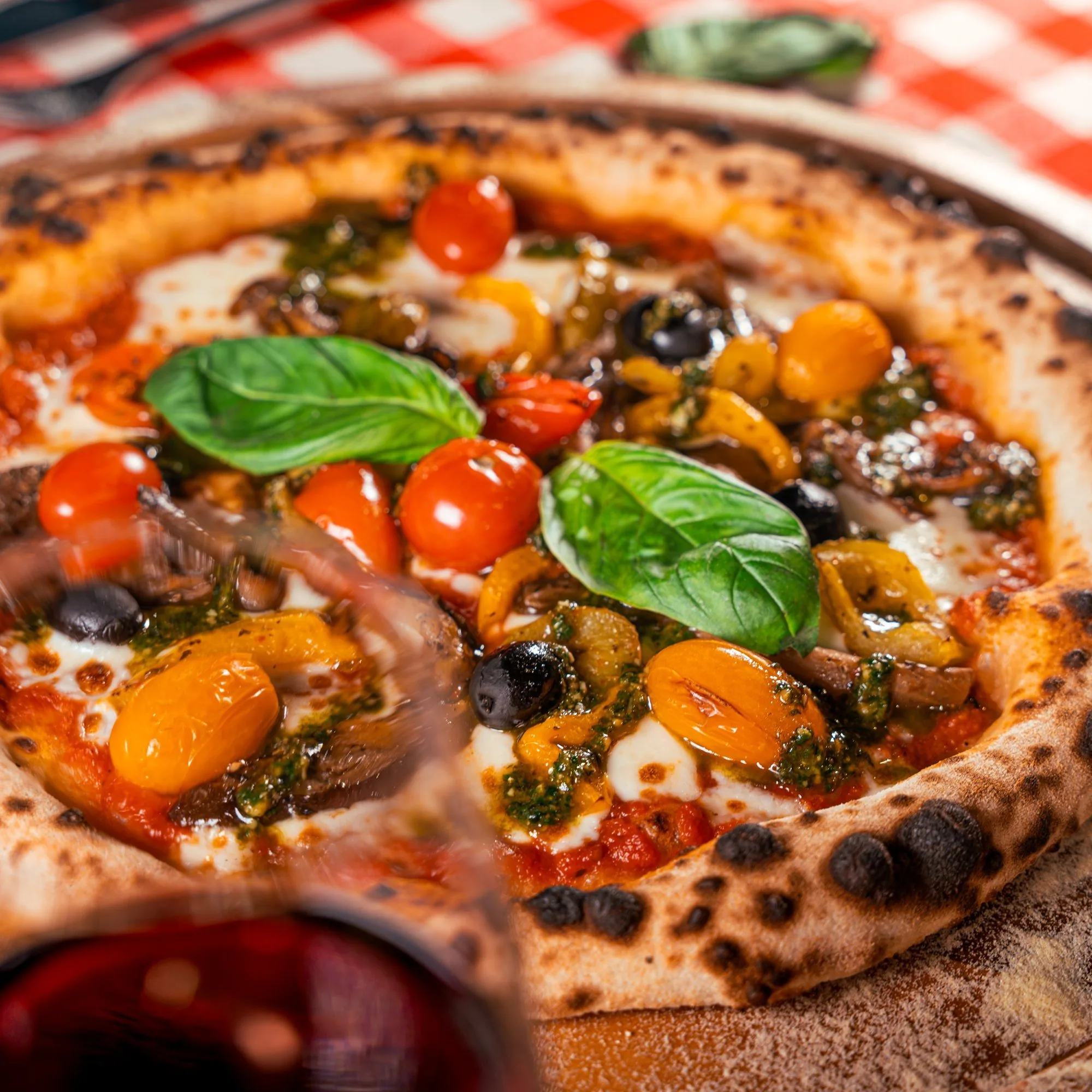 Pizza aux tomates cerises, un verre de vin au premier plan