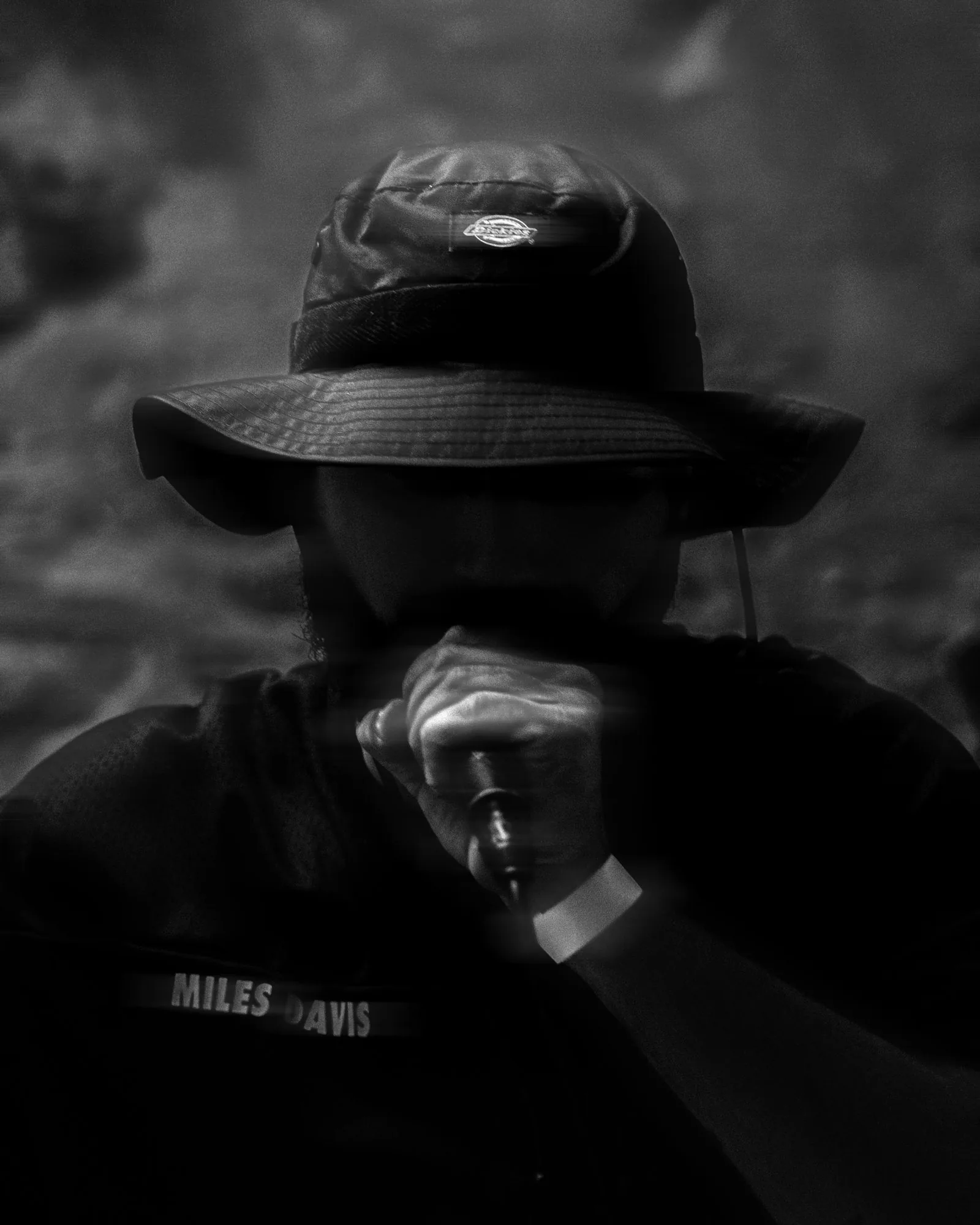 Rappeur au bob, visage dans l'ombre, micro contre la bouche