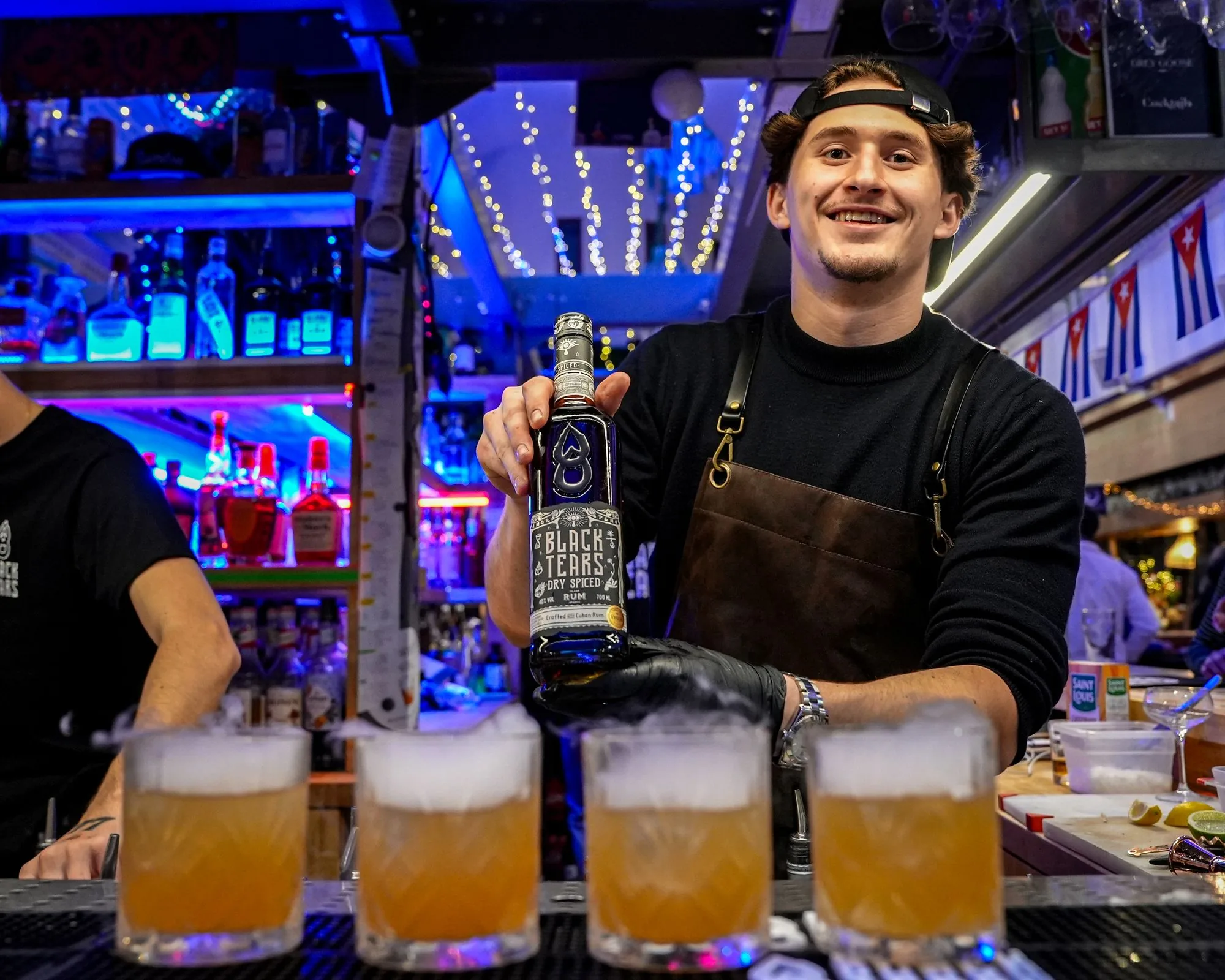Le barman présente la bouteille derrière une rangée de cocktails