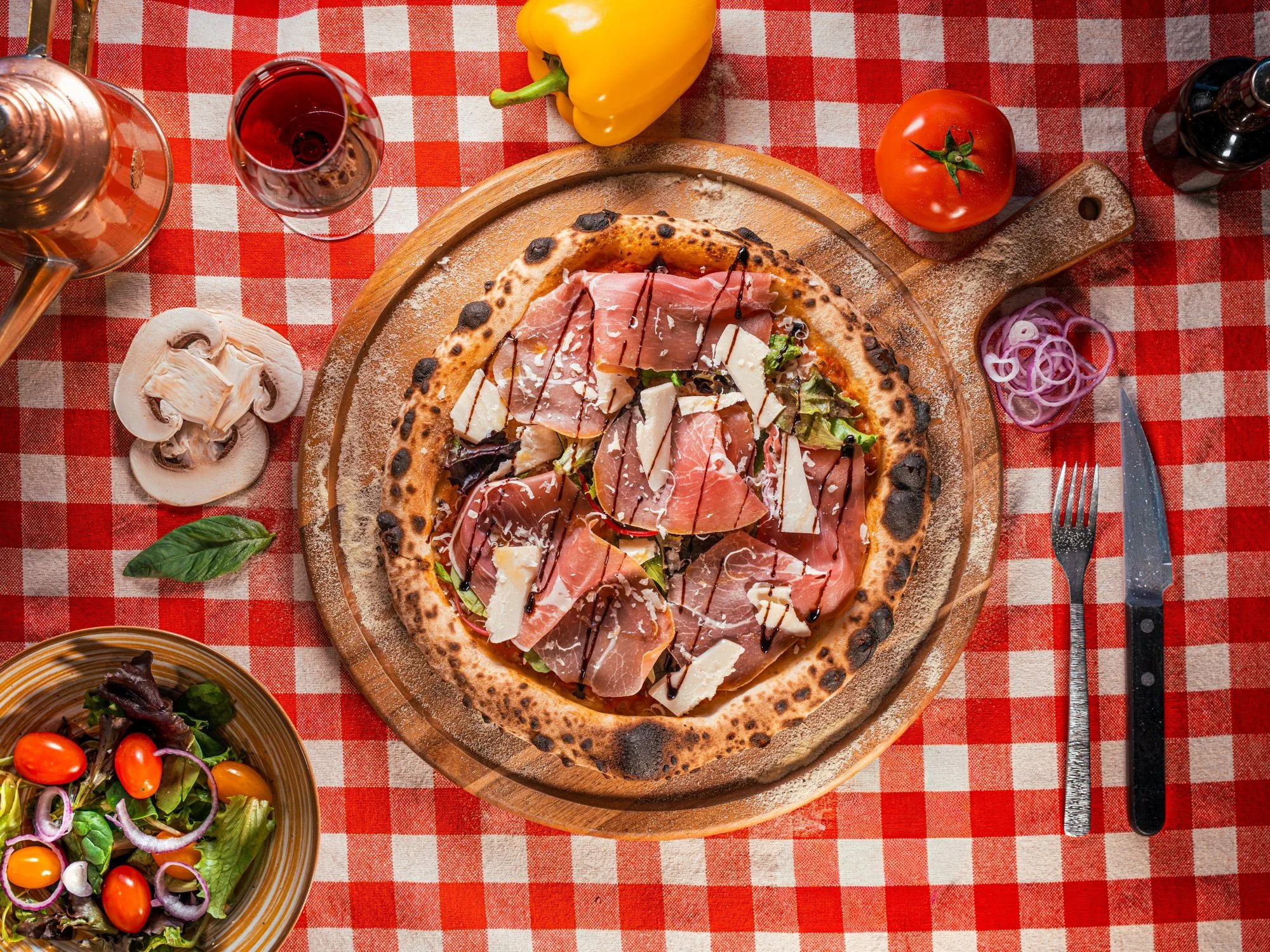 Pizza au jambon cru sur une nappe à carreaux rouges
